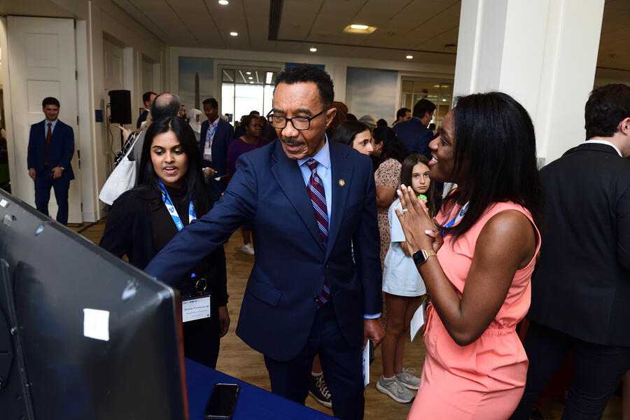 Kweisi Mfume points to something on a TV screen while talking to researchers at Hopkins on the Hill 2025.
