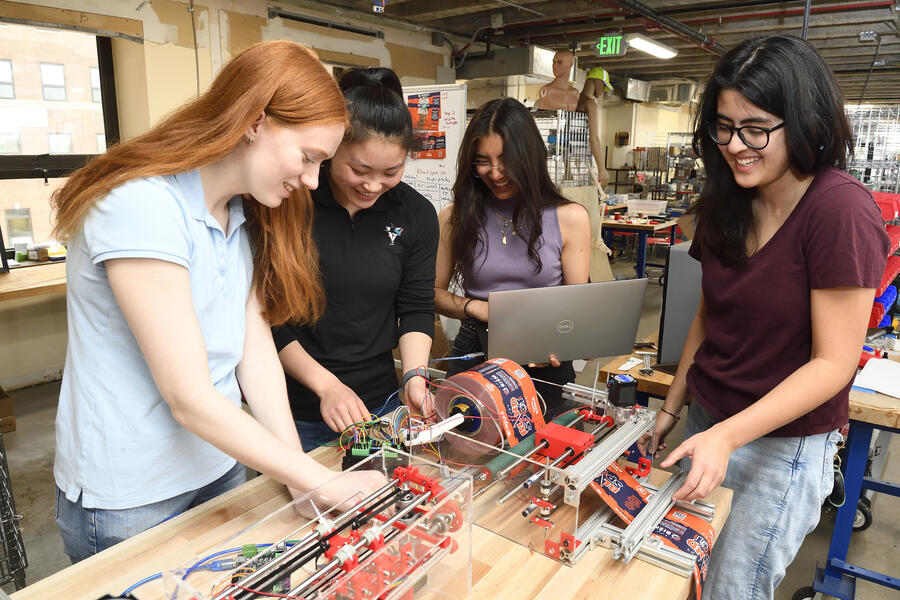 Four students working on a braille printer