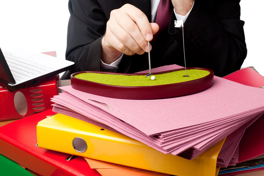 Man at desk playing with a game sitting on top of his work files.