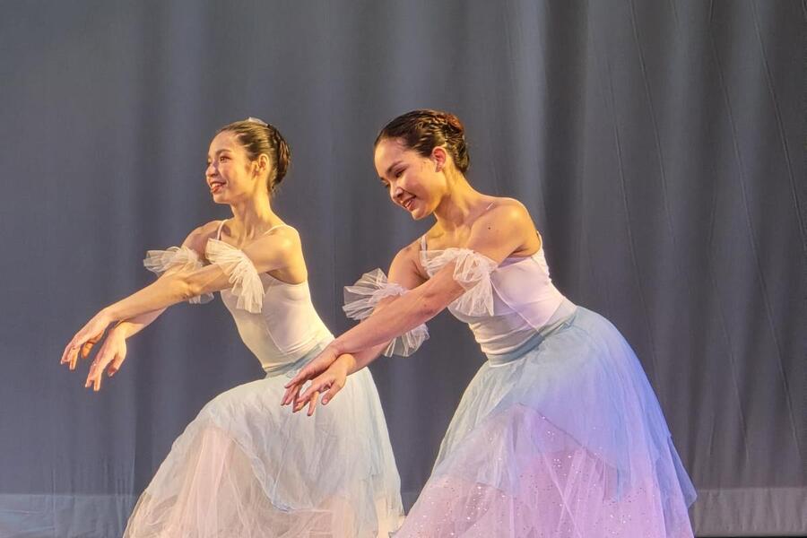 From left, Christine Fernandez and Kaitlyn Kumar kneel on stage as part of a dance in a production of The Nutcracker