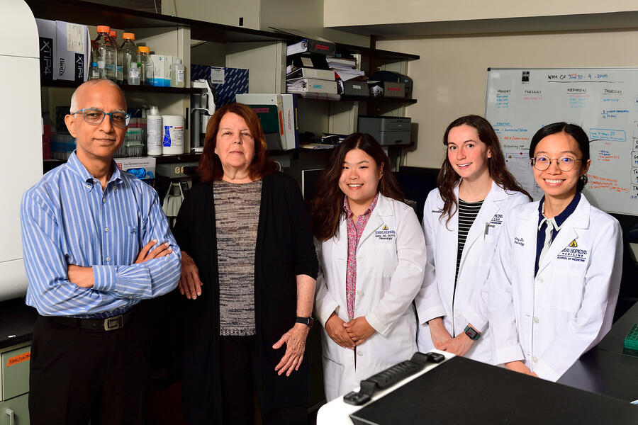 Five people pose for a photo in a lab setting