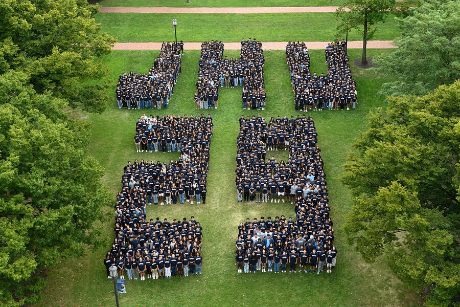 Students from the Class of 2029 are arrayed on a large green space to spell "JHU 29"