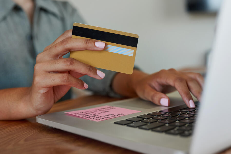 Woman holding credit card as she types on her laptop