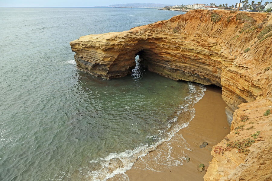 Sunset cliffs natural park in San Diego, California, a beach with a sandstone cliff and city buildings in the background