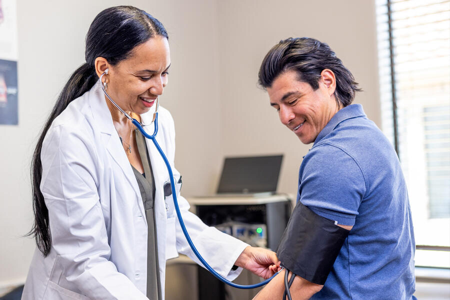 A female doctor checks her male patient's blood pressure