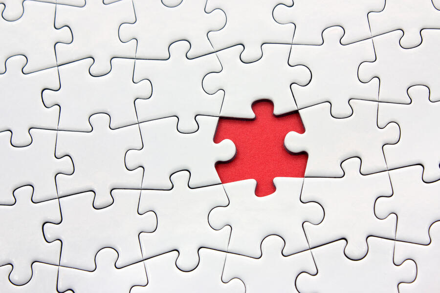 Several white connected puzzle pieces with one missing piece showing a red background beneath