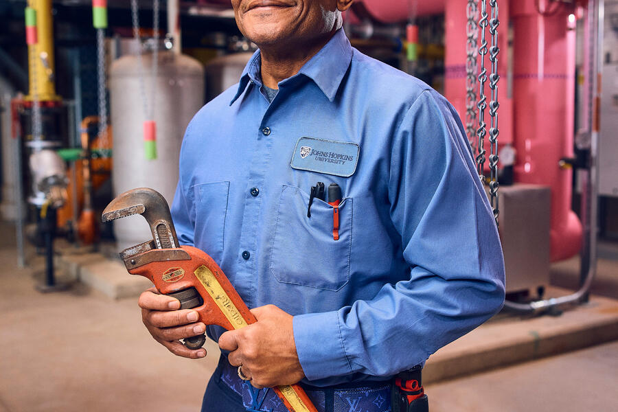 A man holds a large wrench in a posed portrait