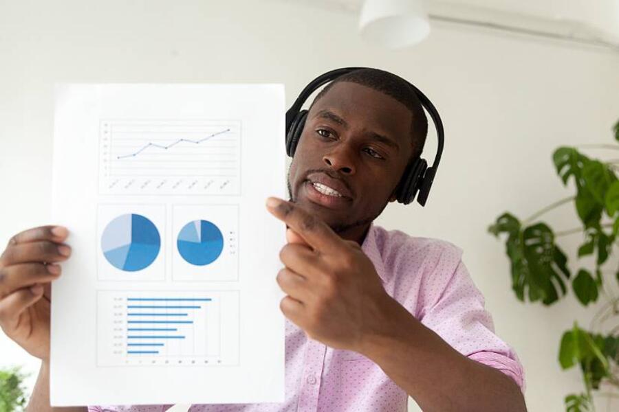 Man holding presentation up to his computer camera