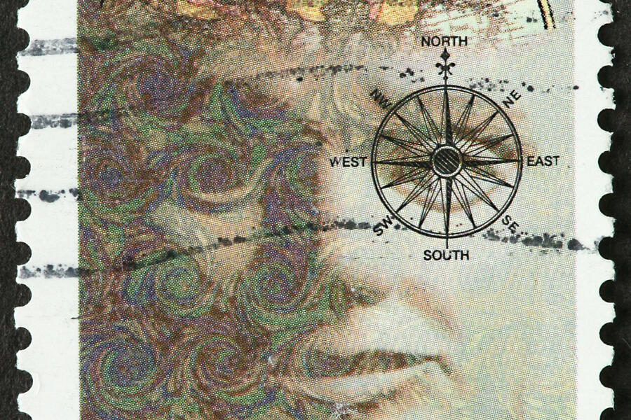 A used stamp that reads "Fulbright Scholarships, USA 32." On it is an abstract depiction of a man with a map in his brain and a compass over his eye.