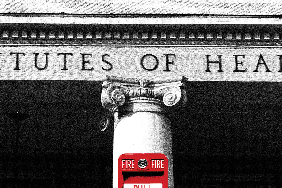 A black and white photo of a pillar on the NIH building. On the pillar is a red fire alarm.
