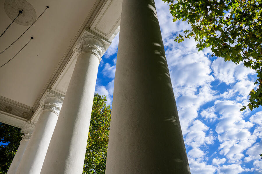 Architectural columns seen against a blue, cloudy sky