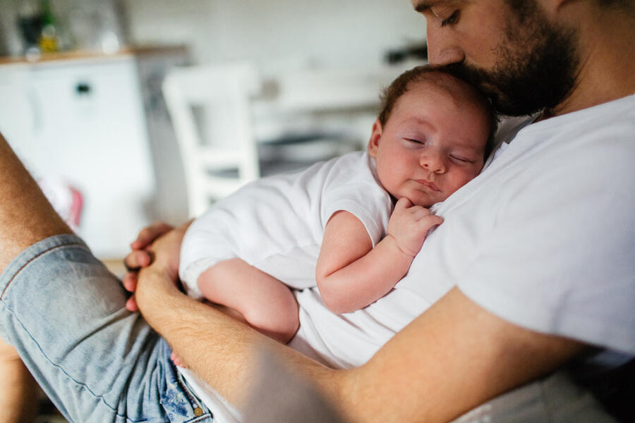 Casually dressed father with infant sleeping on his chest
