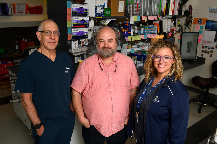 Three people pose in a lab setting