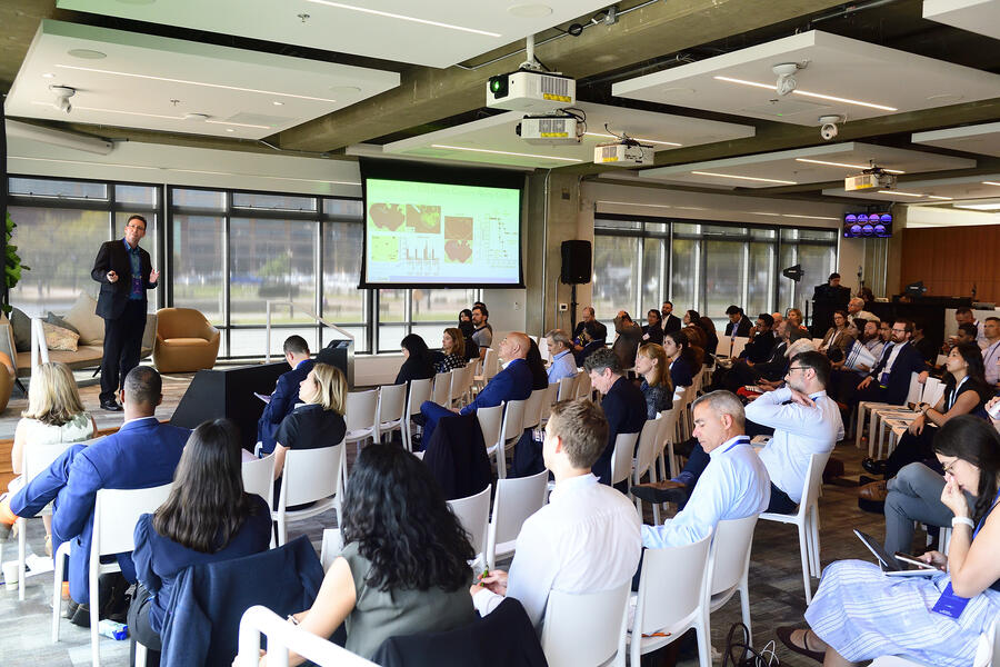 Jordan Green speaks on a stage in front of a large group at the Innovation Summit