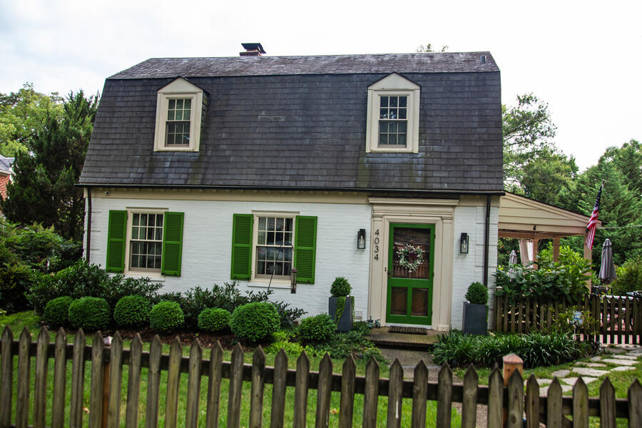 A charming house in Original Northwood, a neighborhood in Northeast Baltimore City. It has shuttered windows and a picket fence surrounding its front lawn.