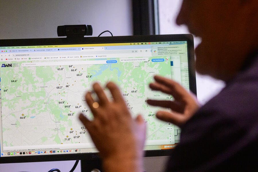 A man in the foreground is silhouetted against a computer screen showing temperature readings on a digital map