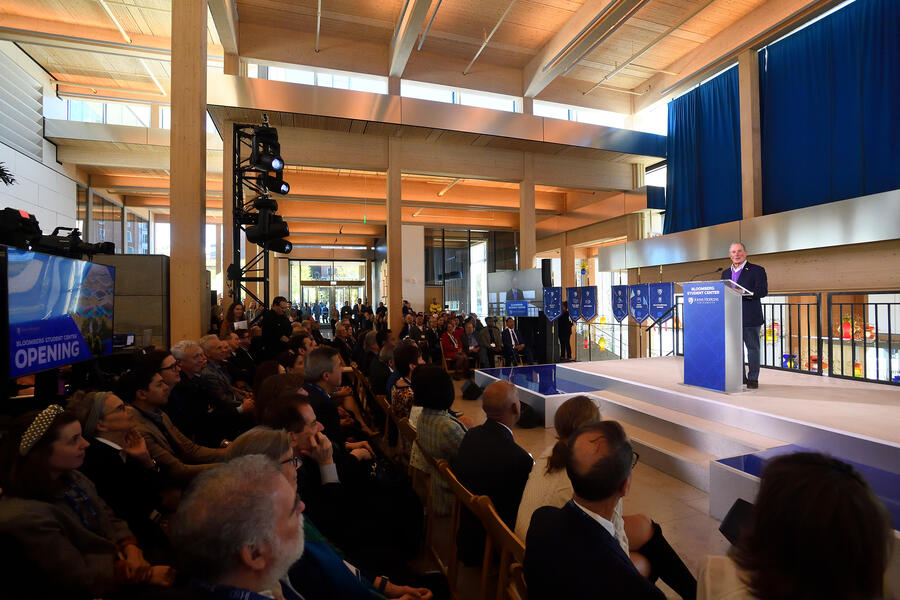 A man stands at a podium speaking to a large audience