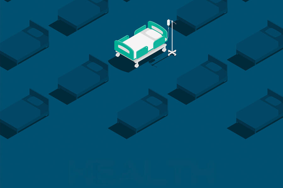 White hospital bed in a blue room with darker hospital beds surrounding it