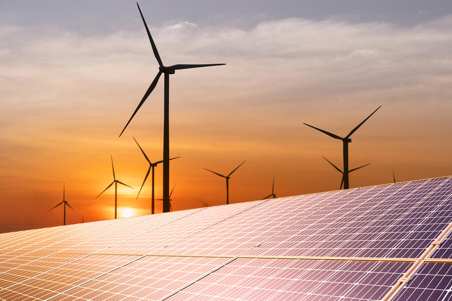 Wind turbine and a solar panel at sunset