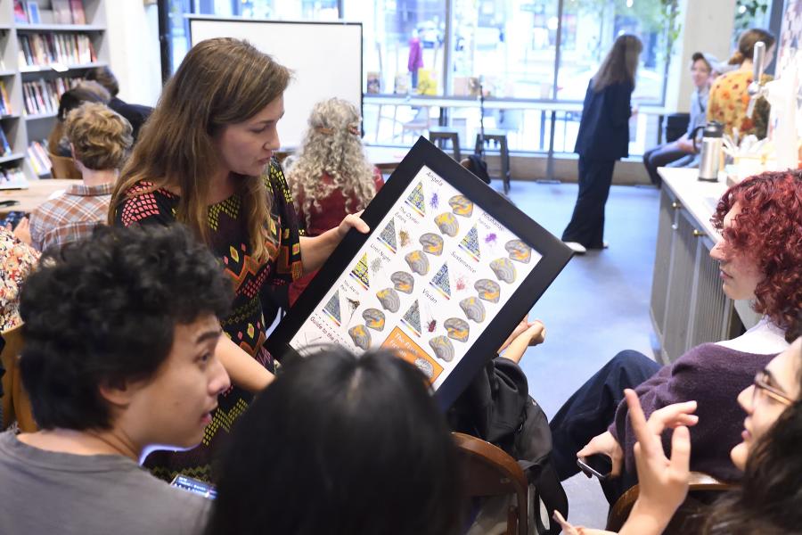 A group of people talk amongst themselves. One is holding up a framed photo of fMRI results.