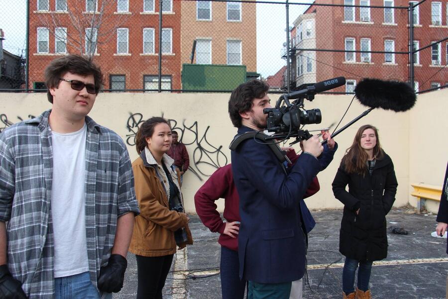 A group of film students with a camera and microphone in an urban playground setting