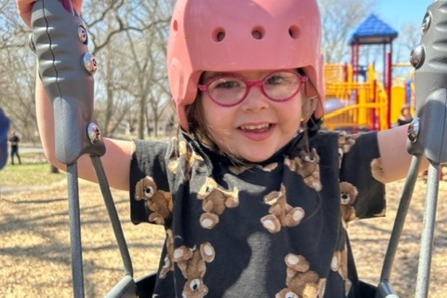Alana "Lani" Silverberg on a swing wearing a pink helmet 