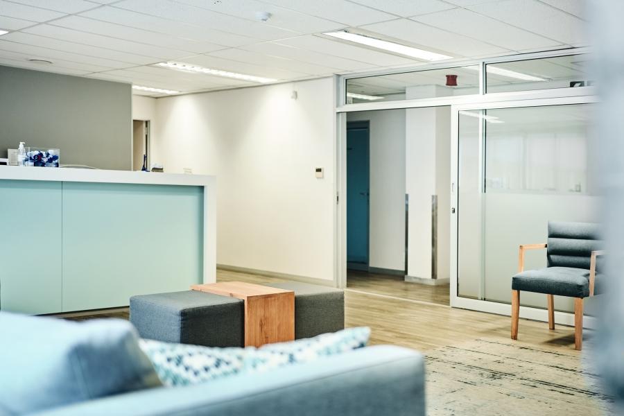 Empty medical waiting room with reception desk and chairs in clean and well-lit clinic lobby