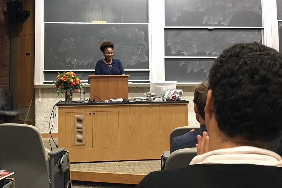 Tracy K. Smith stands at a podium and smiles while the audience applauds her