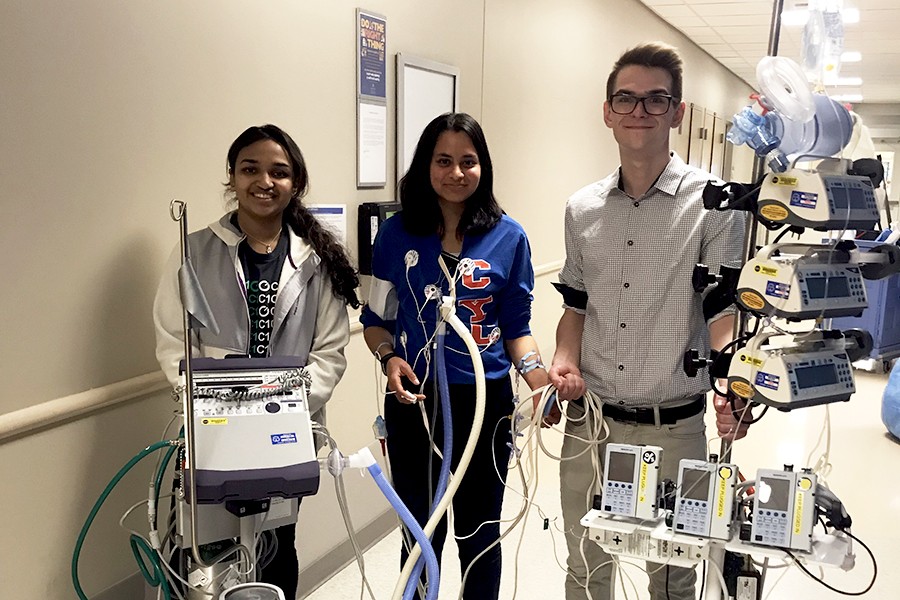 Three students demonstrate a walker built to help ICU patients