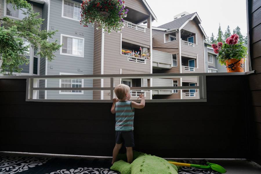 A toddler looks off a balcony at an apartment complex
