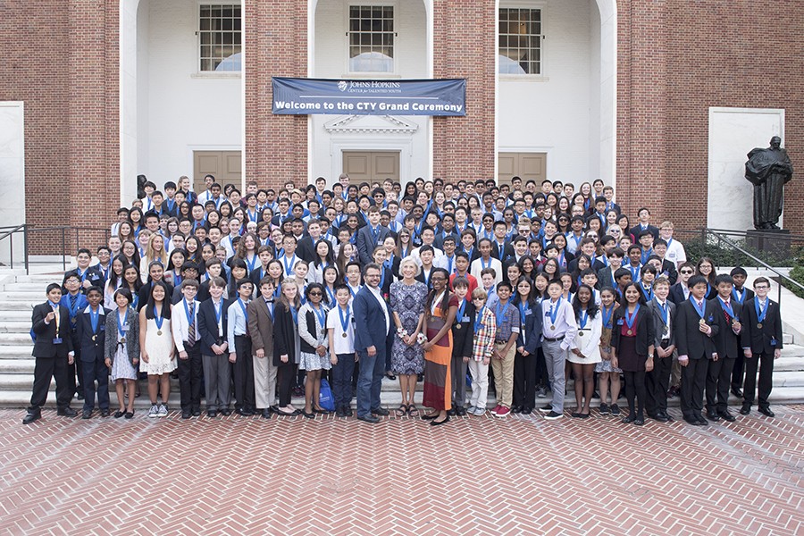 A group of students gather on the steps of Shriver Hall with a few adults photographed in the center