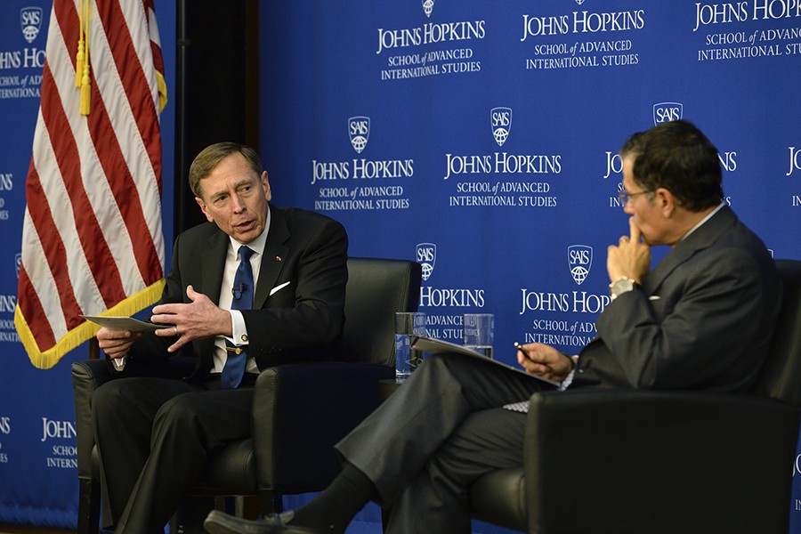 Petraeus gestures and looks at Nasr, who listens with a hand on his chin