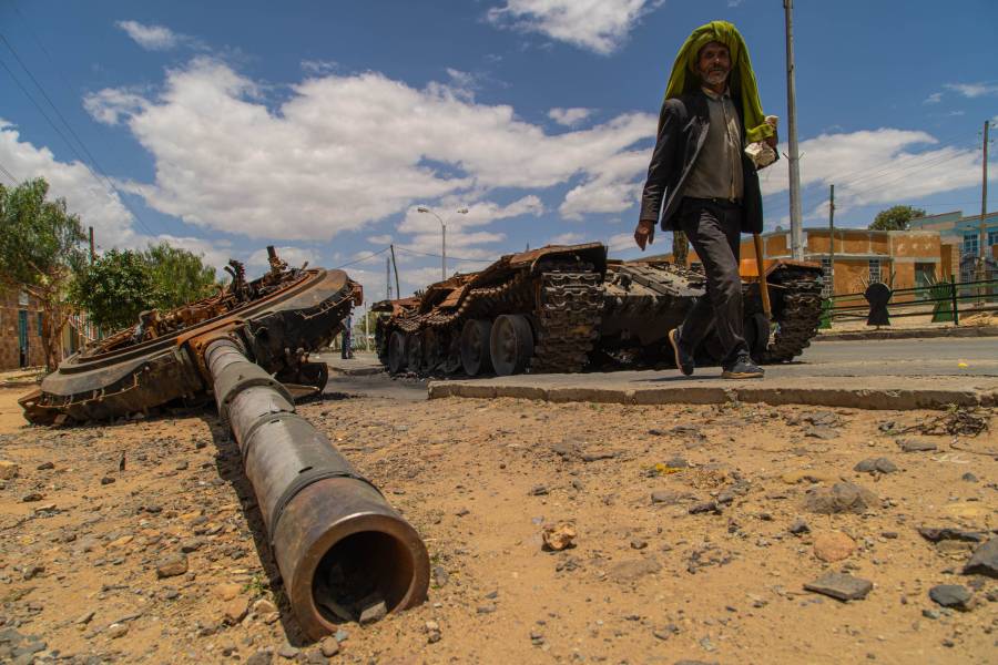 A man walks past a destroyed military tank