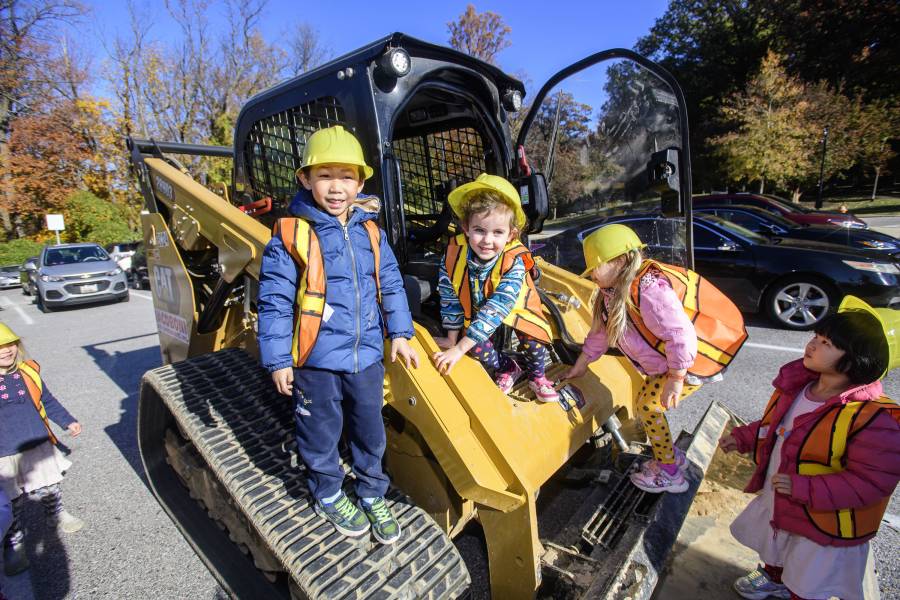 Children smile while climbing on a Bobcat