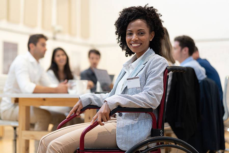 Woman in wheelchair working with colleagues around a table