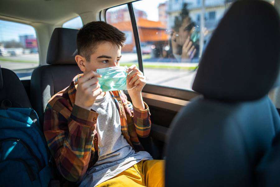 A teenager dons a mask in a car