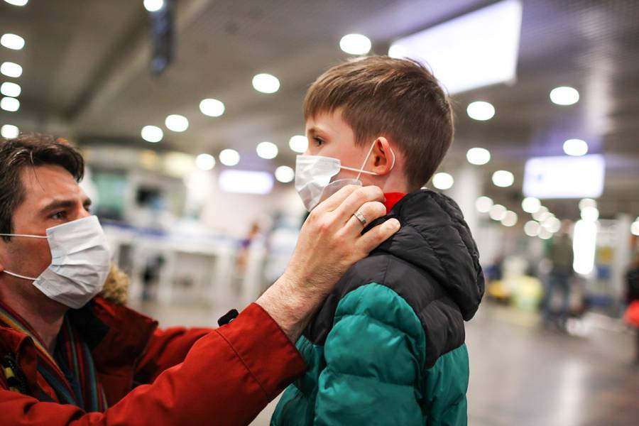 A father adjusts his son's face mask