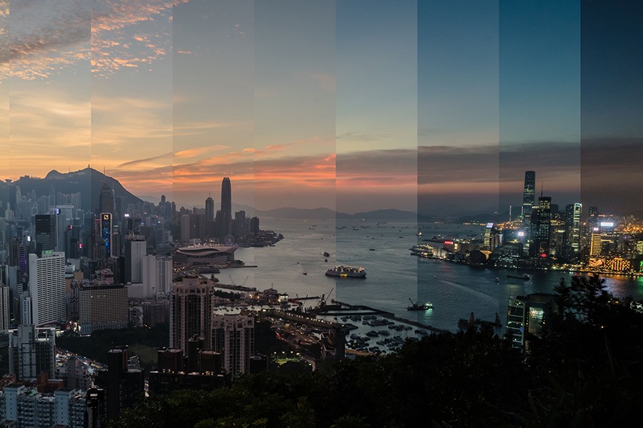 Time-lapse panoramic photo of Hong Kong harbor is sliced into narrow vertical panels each depicting a different time of day, reassembled into one collage-like image