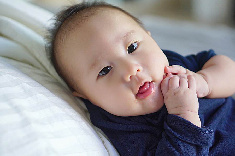 Portrait of a cute baby lying on bed, looking at the camera.