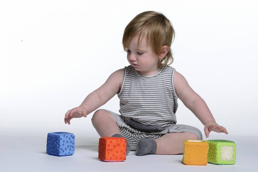 A baby selects a toy from a selection of toys in front of him