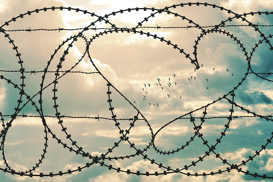 Barbed wire forms a fence, with a heart in the negative space