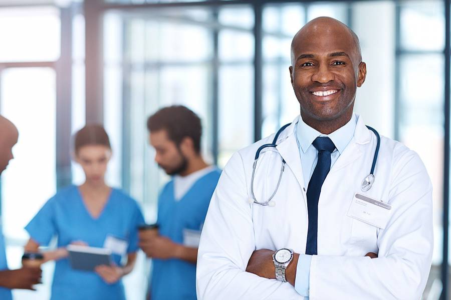 Smiling physician with other medical professionals behind him