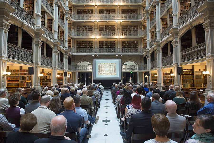 A center aisle divides seats at a presentation inside the historic George Peabody Library