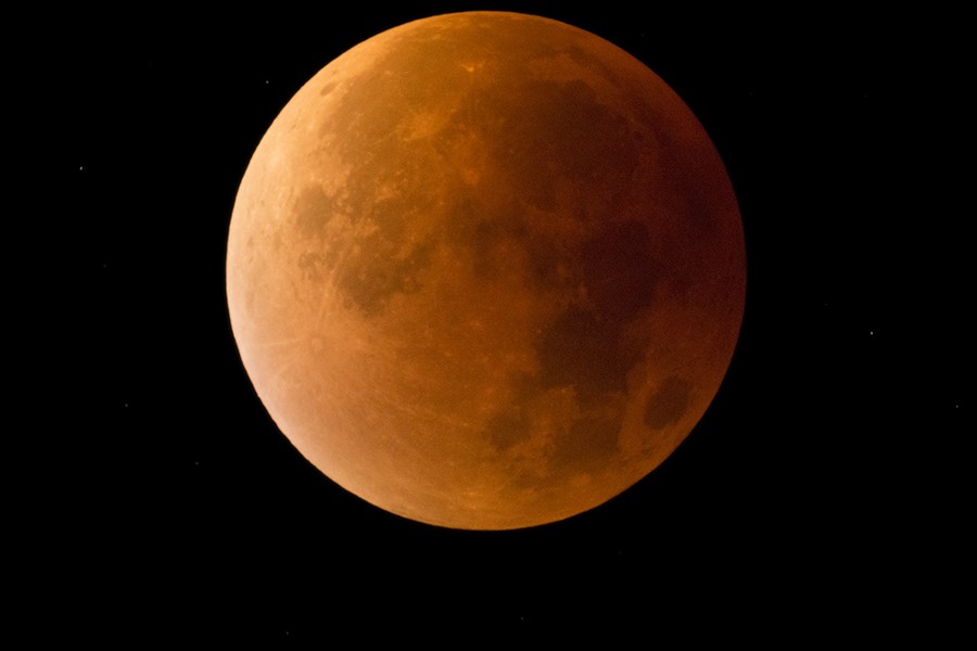 The moon appears in a reddish orange glow