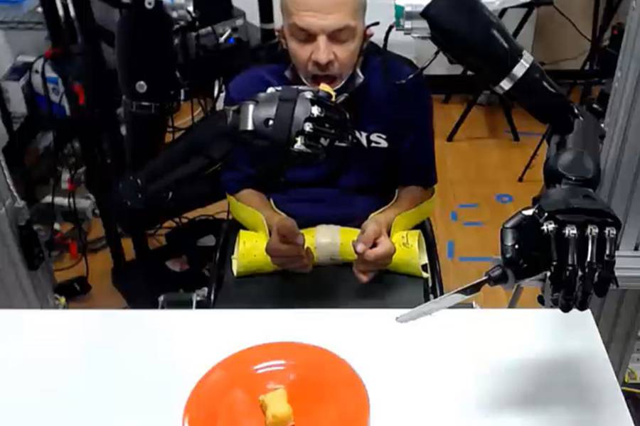 A man is fed by robotic prosthetic arms