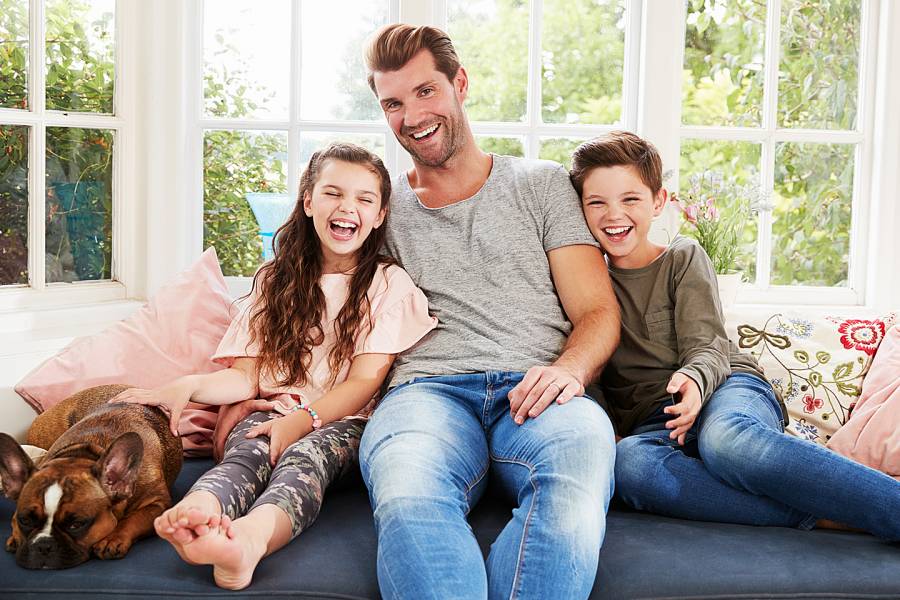 Smiling father and two kids sitting on a couch