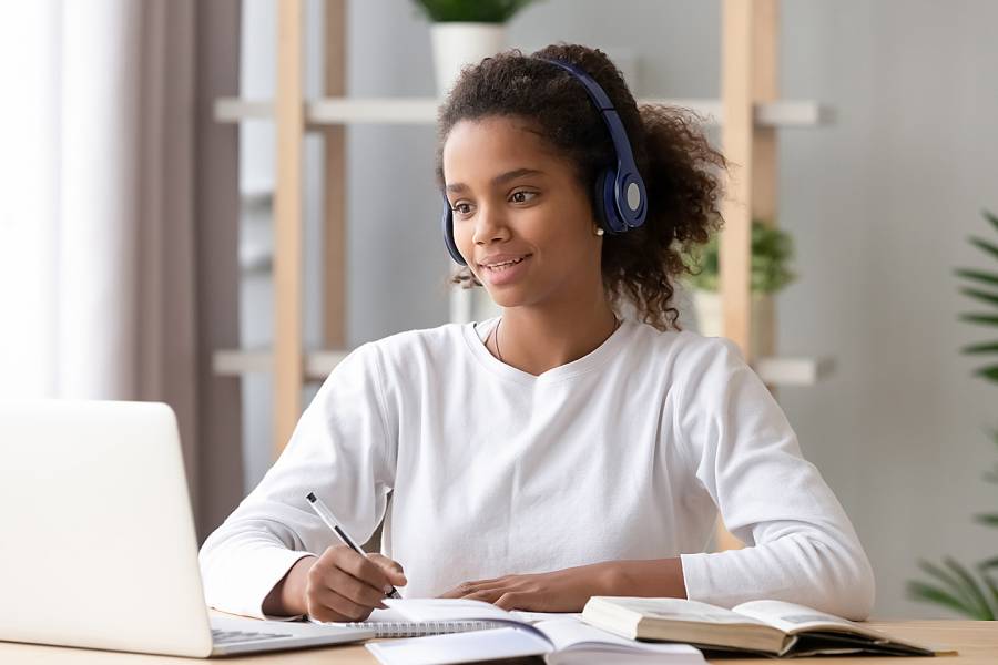 Teenage girl with earphones working at laptop