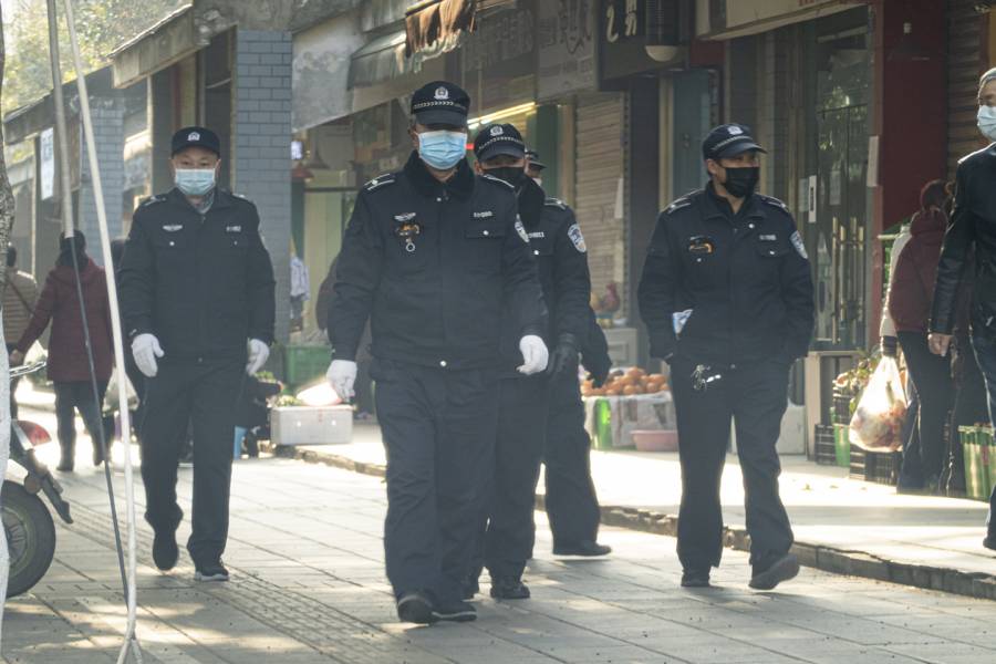 Chinese officials walk down a sidewalk
