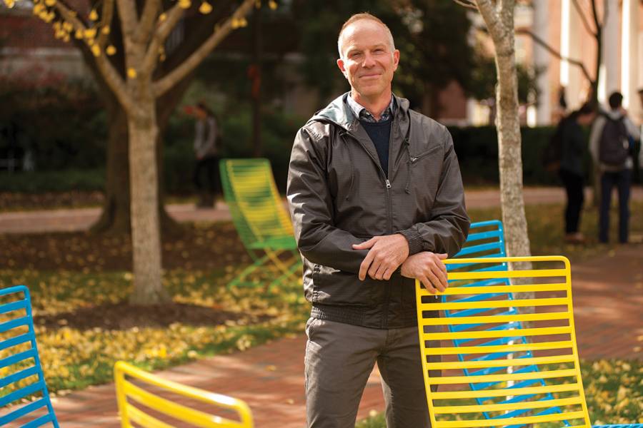 Photograph of Chris Nealon standing next to neon lawn chairs