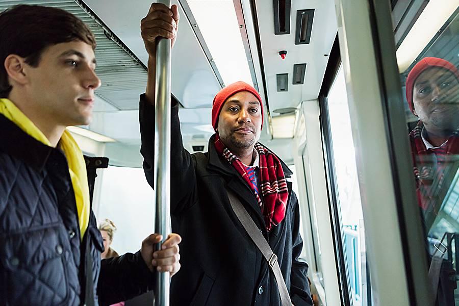 Man holds upright pole on a city bus